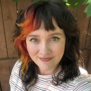 a woman with a brunette shag hair cut with an ombre red color panel wearing a striped shirt